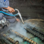 Worker is cleaning the machine equipment by using the air pressu